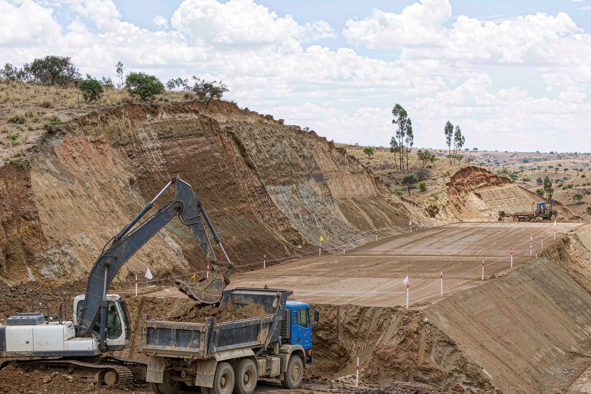 Crawler excavator loading a dump truck on a railway embankment under construction in Kenya